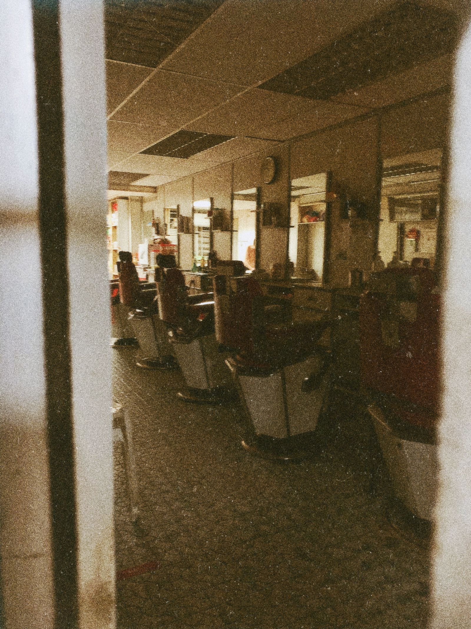Interior de una barbería con sillones, espejos y suelo de madera